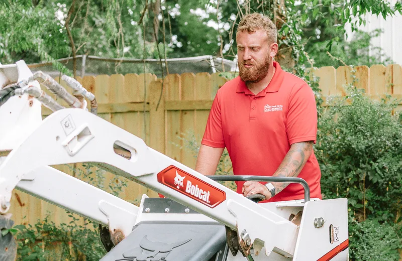 Light demolition services worker operating Bobcat equipment